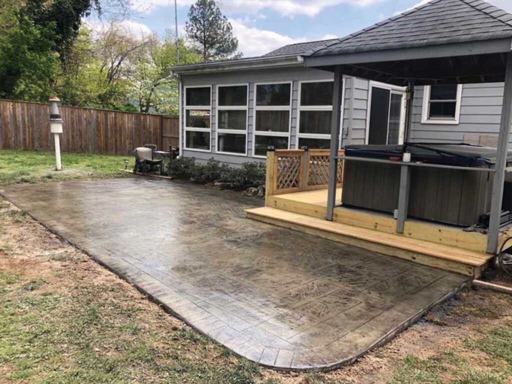Stamped Concrete Patio Beside A Home And Covered Deck.